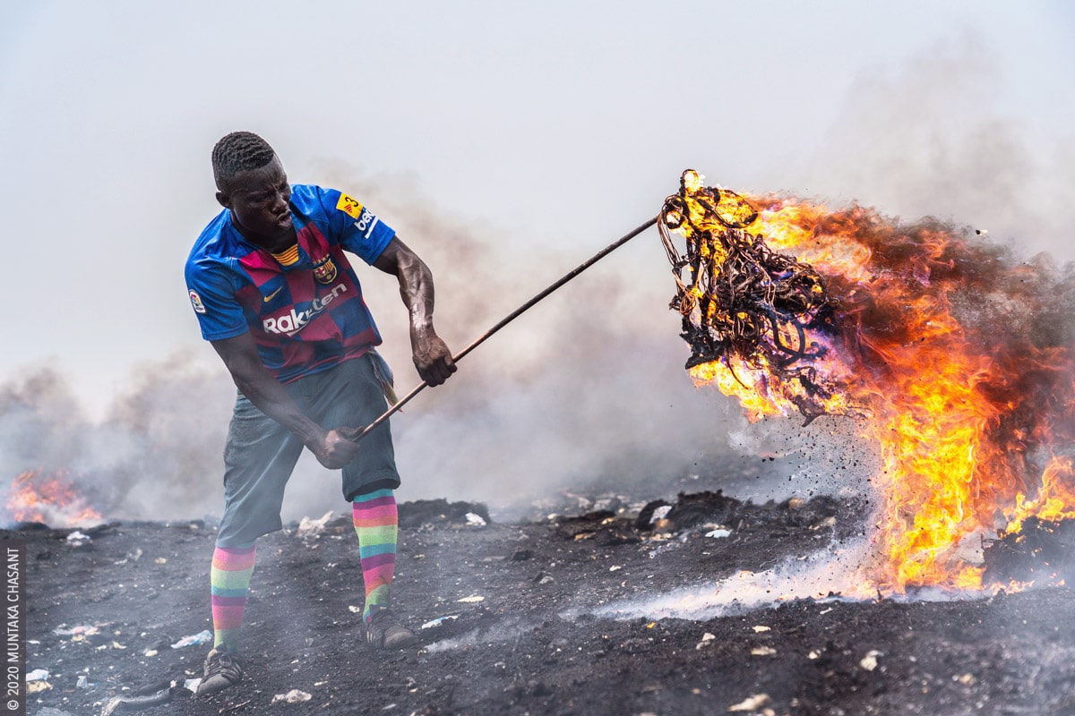 Agbogbloshie: Man is burning electrical wires to recover the copper materials inside at Agbogbloshie, Ghana. © 2020 Muntaka Chasant