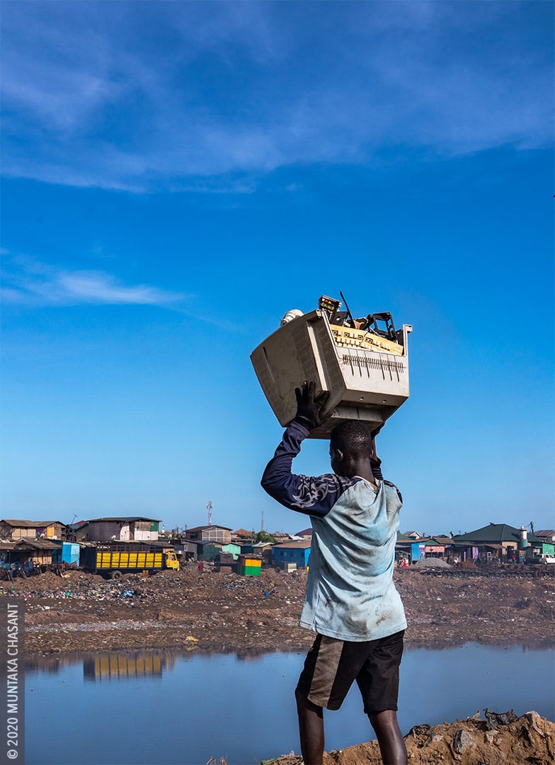 Electronic waste at Agbogbloshie, Ghana: Man is about to dump e-waste near the Korle Lagoon at Agbogbloshie, Ghana. Urban mining, reclaiming valuable materials in the waste stream, is a major source of livelihood for the urban poor at Agbogbloshie. The unsafe dismantling of e-waste at Agbogbloshie pollutes the soil and the Korle Lagoon. © 2020 Muntaka Chasant