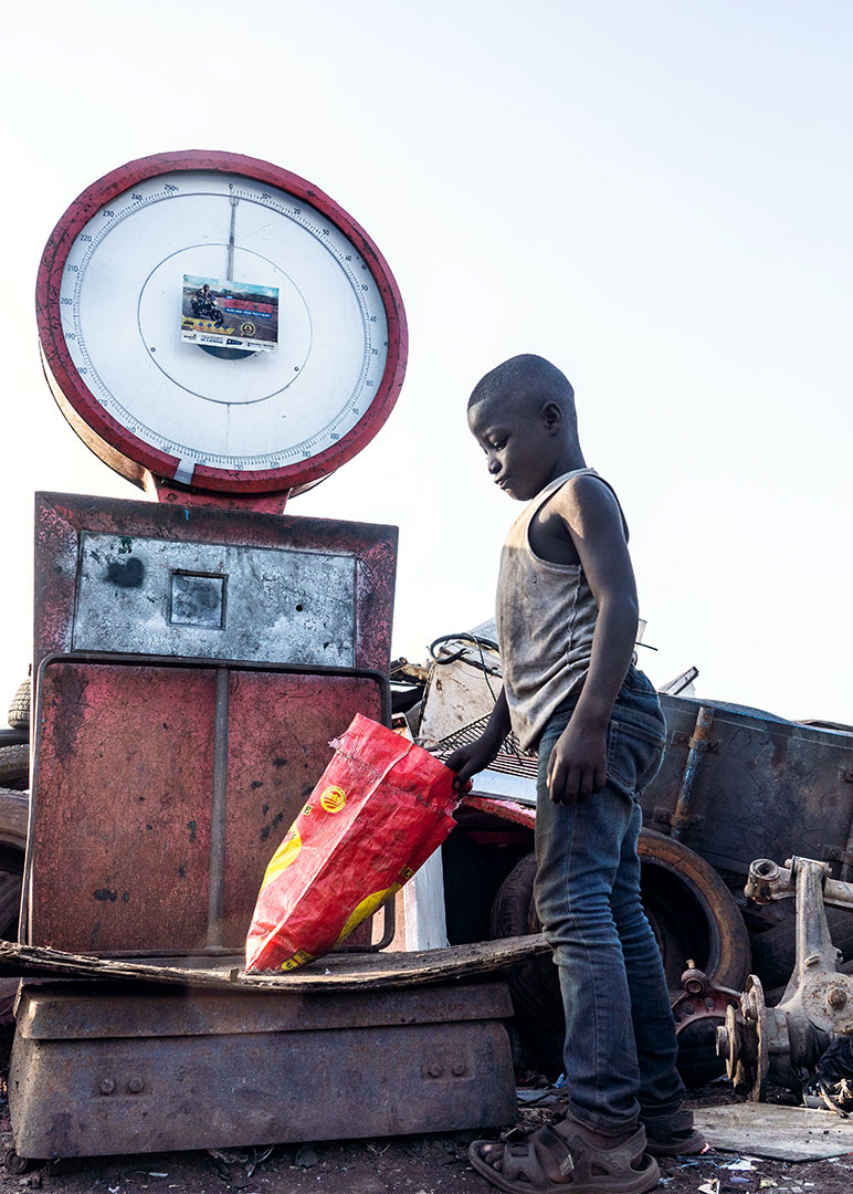 Child Labour in Ghana: 8 years old Akufo-Addo, an hazardous child labourer, is weighing scrap metals at Agbogbloshie, Ghana. More than 24% of children aged 15-14 in Ghana are involved in forced labour. © 2020 Muntaka Chasant