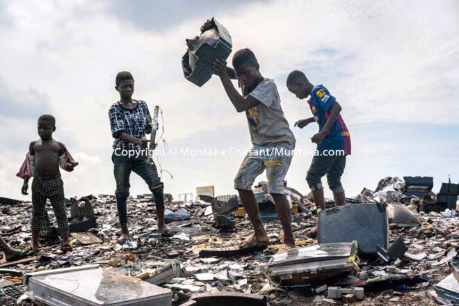 #half Debrah, 15, has just smashed an old CRT TV against a rock to reclaim the iron materials inside. A piece of CRT glass stuck in his hair fell past his left eye, overshadowing it. Debrah is already blind in the left eye and wears a prosthetic. More than 60% of children in hazardous work worldwide are boys, according to ILO estimates. © Muntaka Chasant