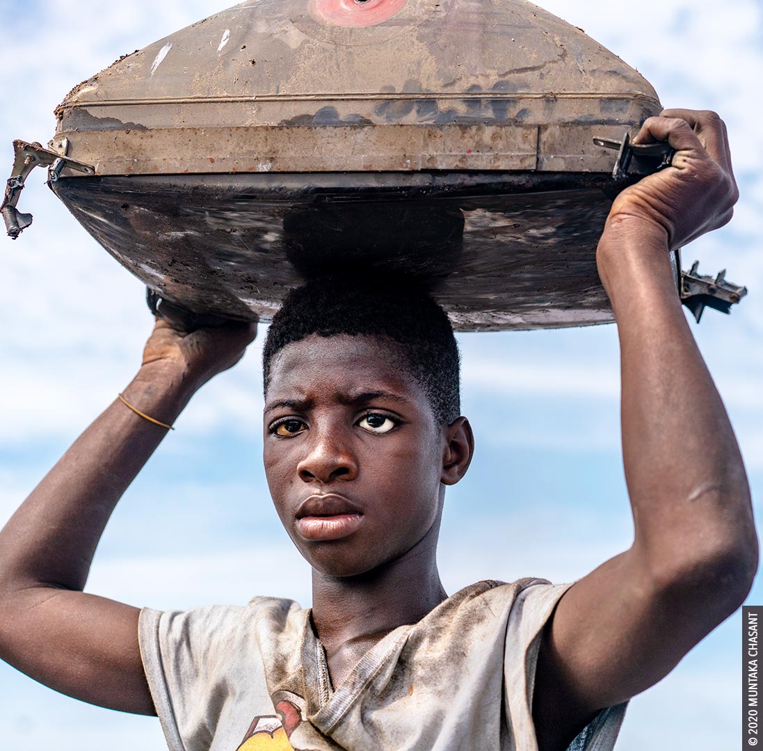 Urban poverty: 15-year-old Kwaku Debrah is an urban poor boy engaged in hazardous child labour on the fringes of Agbogbloshie, Ghana. He’s blind in the left eye and wears a prosthetic. According to a recent report, more than 62% of urban children in Ghana aged 0 -17 years are multidimensionally poor (deprivations such as lack of proper nutrition, basic sanitation, and housing). © 2020 Muntaka Chasant
