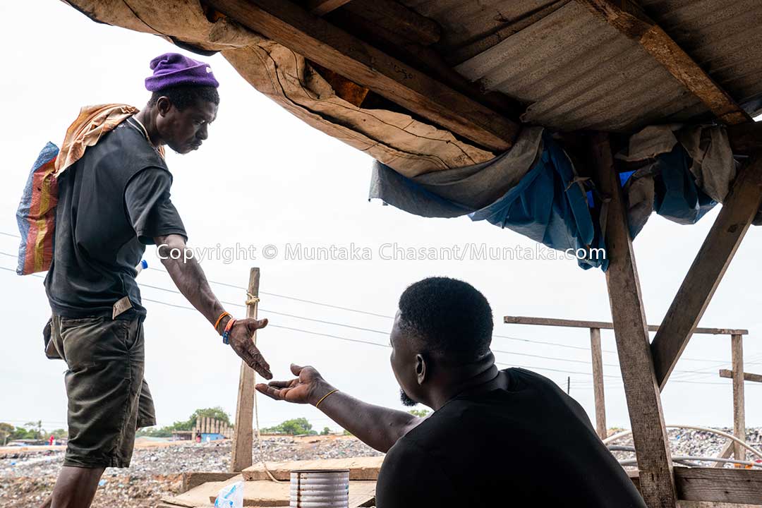 Man pays a toll to cross a makeshift wooden bridge. Sodom and Gomorrah, Accra, Ghana. Copyright © 2020 Muntaka Chasant