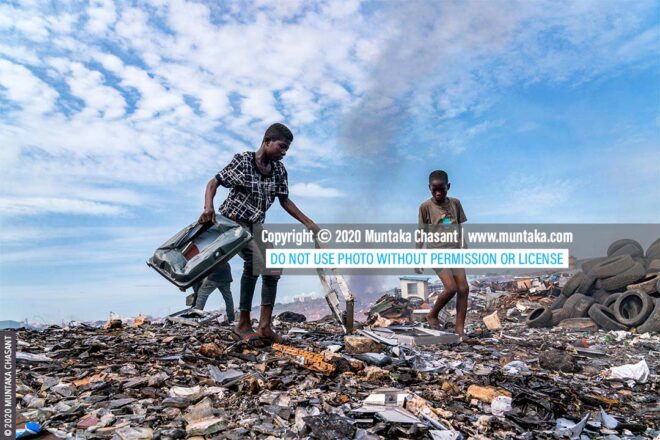 Children working in a toxic environment: Osei, 15 years, and Mustafa, 13 years, are using stones to break apart old television sets to reclaim the iron materials inside at Agbogbloshie, Ghana. © 2020 Muntaka Chasant