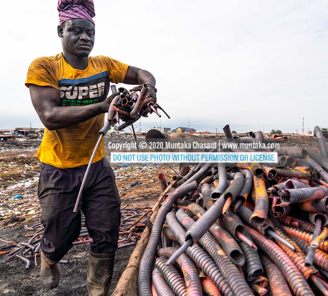 Recycling heliax cables at Agbogbloshie: Man arranges copper materials from burned heliax coaxial cables to be carted away. Copyright © 2020 Muntaka Chasant