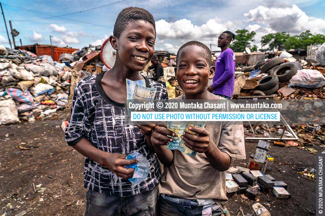 Child labour: Osei, 15 years old, and Mustafa, 13 years, engaged in hazardous child labour in Ghana smile and display how much they had earned for the morning. They had earlier used bare hands and stones to break apart old CRT TVs for the iron-nickel alloy materials inside. They sold the precious metals for around $0.15 per kilo at Agbogbloshie, earning them GH₵10 each (around $1.74). They were exposed to heavy metals such as lead, cadmium, and barium. Around 152 million children worldwide are victims of child labour, with 73 million engaged in hazardous work, the ILO statistics show. © 2020 Muntaka Chasant