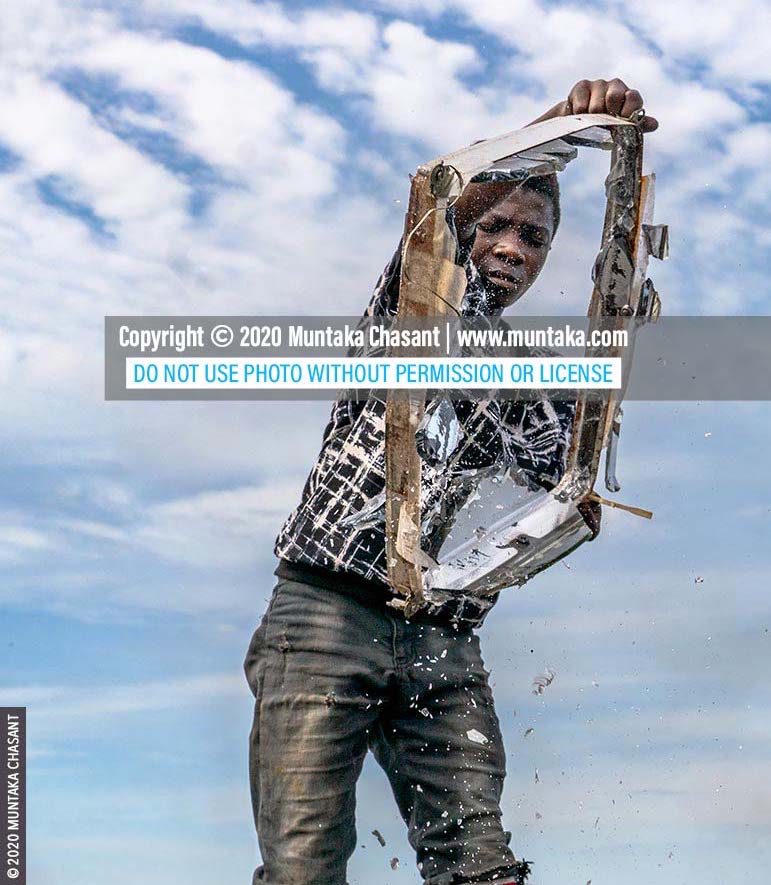 E-waste recycling: Osei, 15 years old, shakes off panel glass from an old CRT TV part at Agbogbloshie, Ghana. Old television sets are smashed against stones sometimes to separate the glasses from the iron metal components inside. They are then sold for around $0.15 per kilo (in May 2020) at Agbogbloshie. © 2020 Muntaka Chasant