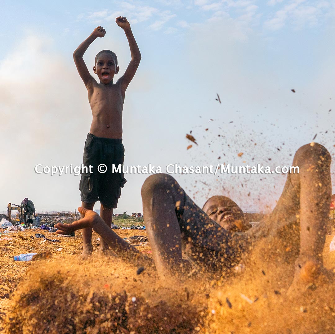 Agbogbloshie slum children have fun in sawdust inside the Sodom and Gomorrah settlement near the center of Accra, Ghana's capital city. Children living in urban poverty are facing severe social and material deprivation. Their fault is that they live far out of the mainstream, thus excluded from all social progress. Not even a proper playground to nurture their dreams and aspirations. No tunnels, swings, and slides. According to a study cited in a UNICEF report, about half of sub-Saharan Africa and South Asia's children even go unregistered at birth. Poor urban children have limited access to essential services such as clean water and sanitation systems. Agbogbloshie 2020. © 2020 Muntaka Chasant
