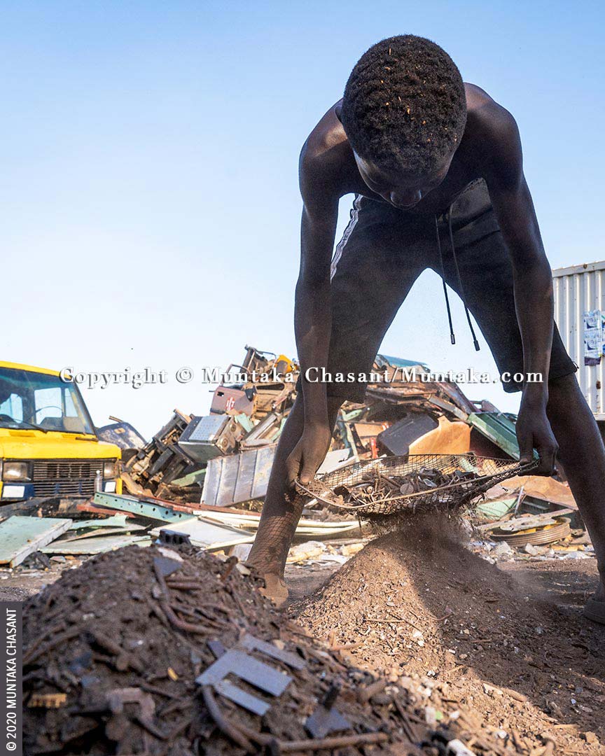 Child labour in Africa: Osei, 15 years old, is engaged in hazardous child labour on the margins of Agbogbloshie, Ghana. He is separating nails, crown cork bottle caps, and other small metals from dirt before selling them for around $0.15 per kilo at Agbogbloshie. More than 72 million children in Africa are estimated to be in child labour, with 31.5 million, more than Ghana’s population, engaged in hazardous work. © 2020 Muntaka Chasant