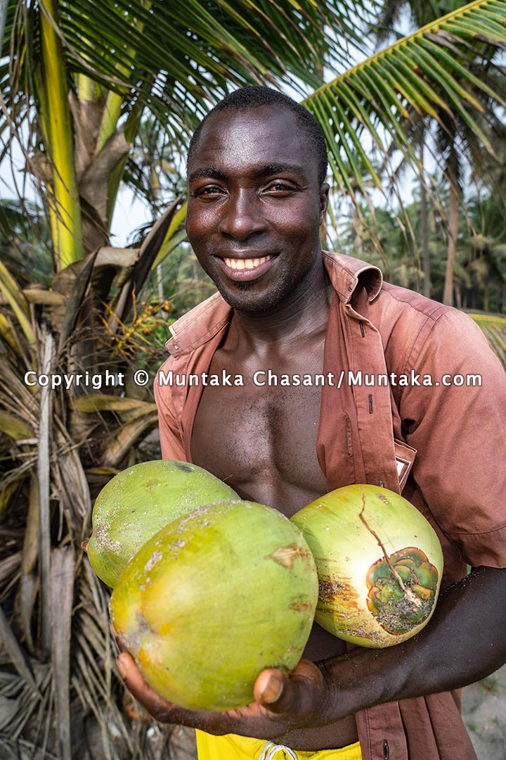 Man smiles after plucking coconuts on the coast of Ghana. Copyright © 2021 Muntaka Chasant