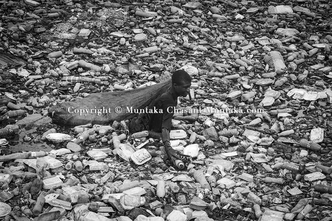 Youth poverty: A frustrated young Ghanaian man swims in the heavily polluted Kore Lagoon to recover recyclable plastics and cans. Copyright © Muntaka Chasant