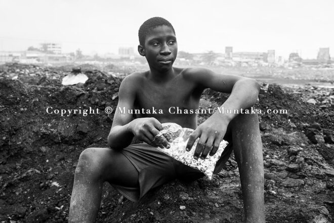 A teenager engaged in hazardous child labour takes a break to eat popcorn at Agbogbloshie, Accra, Ghana. Copyright © Muntaka Chasant