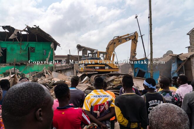 Old Fadama residents anxiously watch on as an excavator demolish sections of the settlement. Copyright © Muntaka Chasant