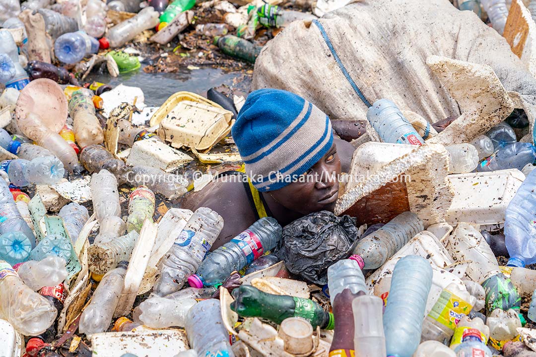 An urban poor man swims in a heavily polluted lagoon to recover recyclable plastics. Ghana is facing a severe plastic pollution crisis. Copyright © Muntaka Chasant
